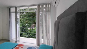 Une pièce dotée d’une grande porte-fenêtre coulissante donnant sur un balcon, d’un canapé gris et d’un tapis à motifs.