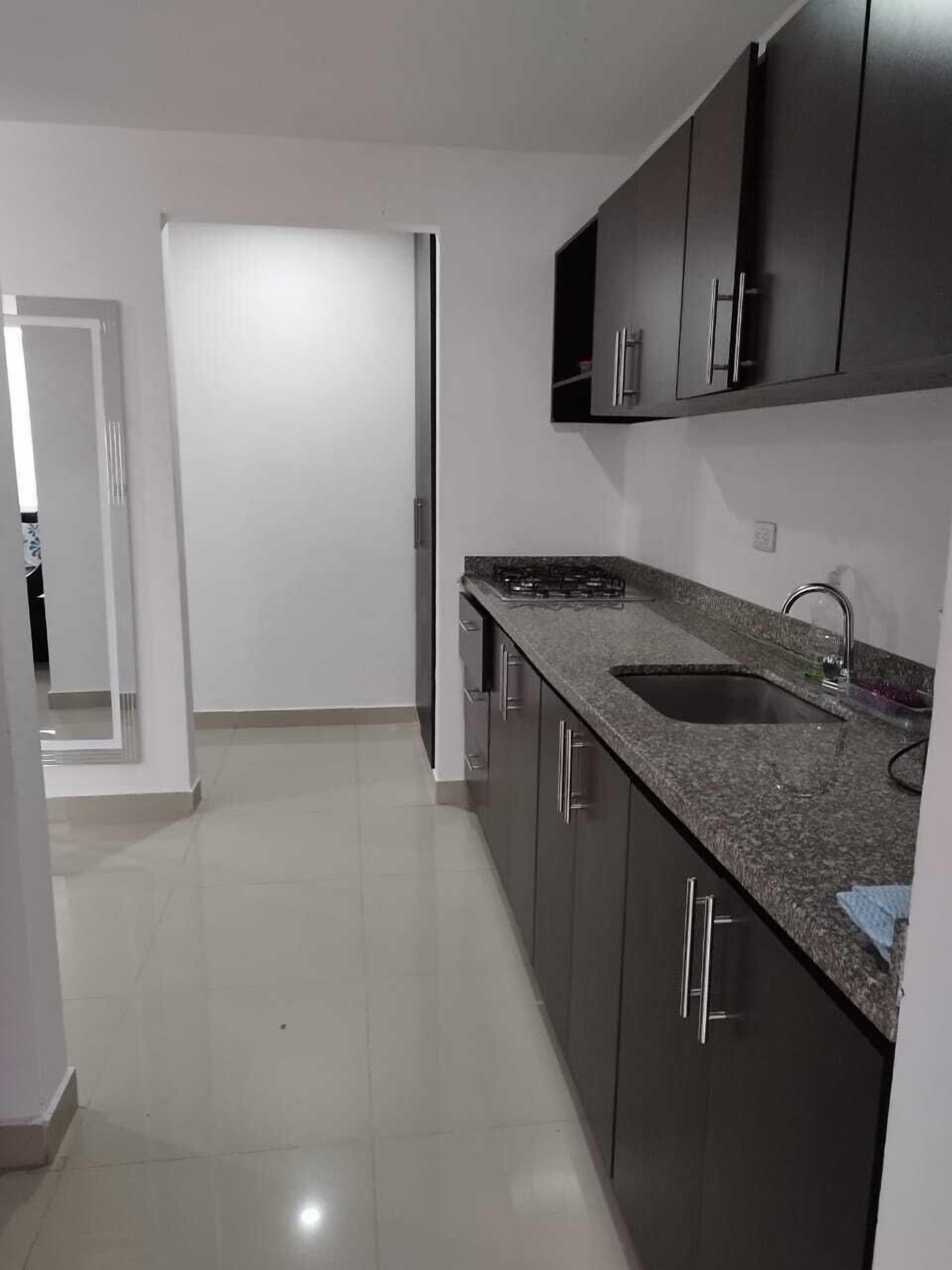 A kitchen with dark cabinets, a granite countertop, and a stainless steel sink.