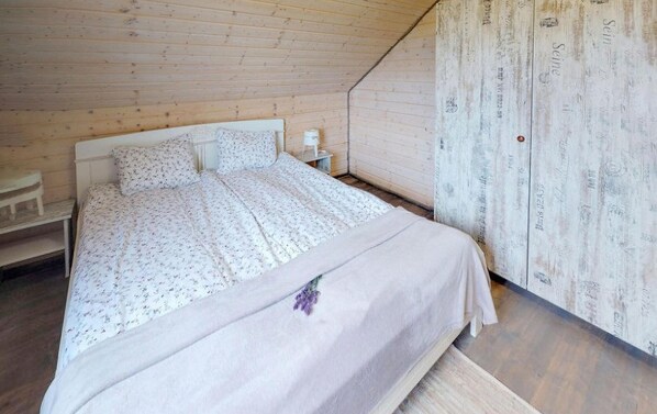 A bedroom with a wooden ceiling, a bed with a floral bedspread, a nightstand, and a wall with decorative text. - Stunning home in Karwia with heated swimming pool (Karwia)