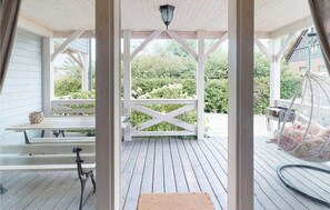 A covered porch with a wooden bench, a hanging bird feeder, and a view of greenery. - Stunning home in Karwia with heated swimming pool (Karwia)