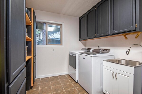 A compact kitchen with a washer and dryer, dark cabinets, and a window.