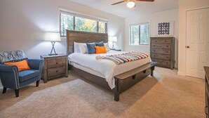 A bedroom with a bed, nightstands, a chair, a dresser, and a ceiling fan. - 5 Wickiup - Hot Tub, Updated, Ping Pong, SHARC Passes, Bikes (Sunriver)