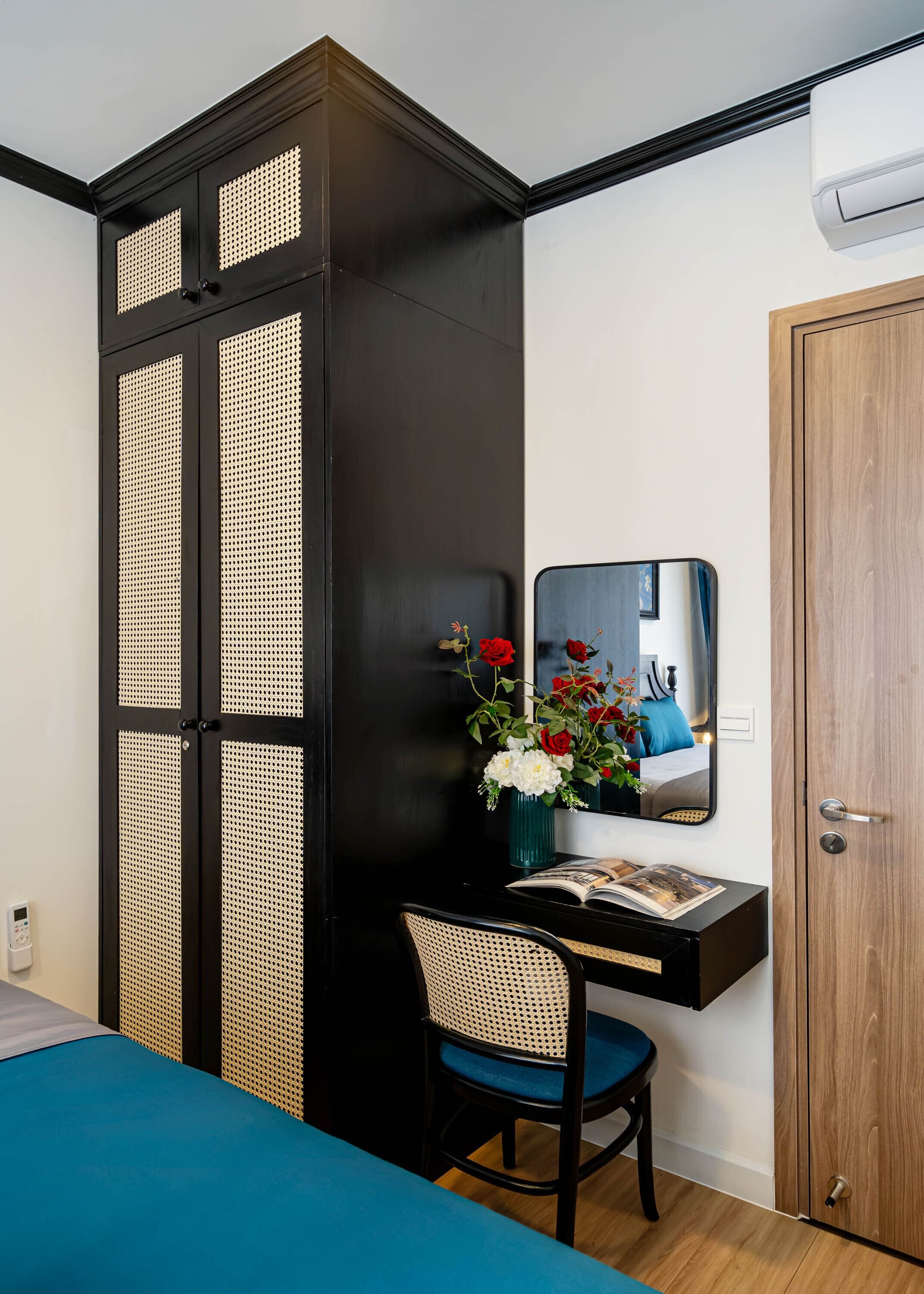A room with a bed, a desk with a chair, a mirror, and a wardrobe.