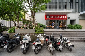 A row of parked scooters in front of a building with a sign that reads 'PHINDELI' and 'SOHO'. - SOHO Residence & Hotel (Ho Chi Minh City)