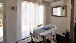 A dining area with a white table, chairs, and a hanging light fixture.
