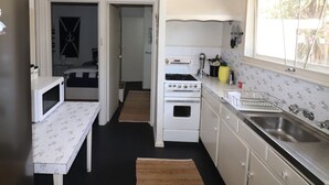 A compact kitchen with a microwave, stove, and sink.