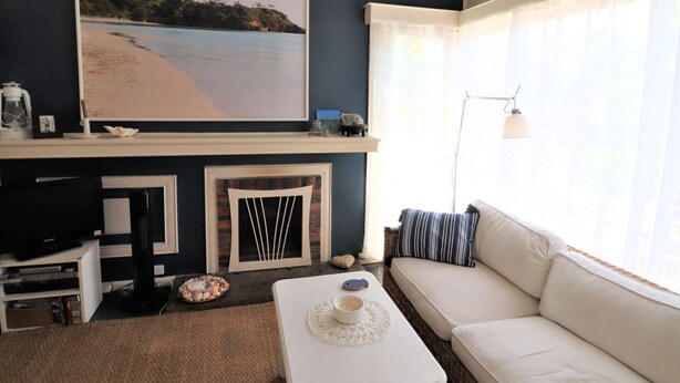 A living room with a fireplace, a sofa, a coffee table, and a large framed picture of a beach.