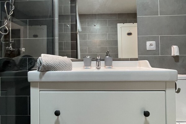 A bathroom with a white sink, two faucets, and a towel on the counter.