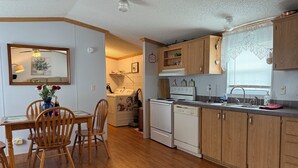 Una cucina con mobili in legno, un tavolo da pranzo con sedie, una lavatrice e un fornello.