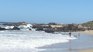 Ein Strand mit Felsen und brechenden Wellen.