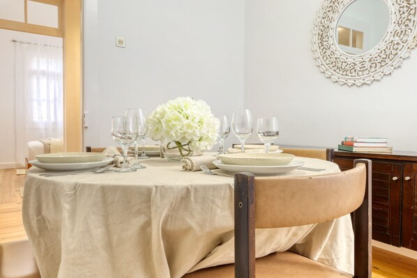 Ett matbord dukat med tallrikar, glas och en vas med blommor.