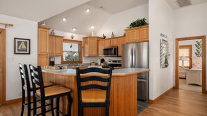 A modern kitchen with wooden cabinets, stainless steel appliances, and a central island with bar stools.