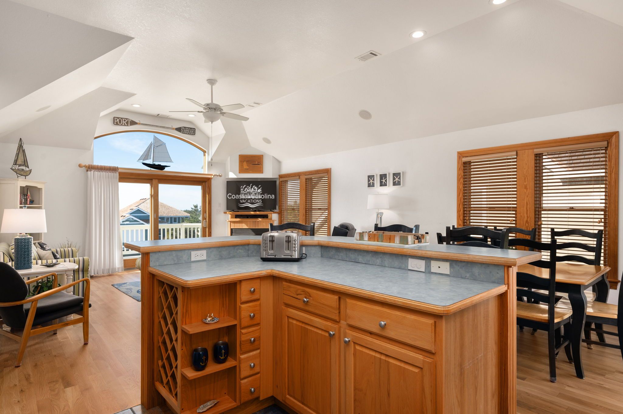 A spacious kitchen with wooden cabinetry, a built-in island, and a large window overlooking a balcony.