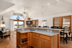 Una cocina amplia con armarios de madera, una isla integrada y un gran ventanal con vistas a un balcón.