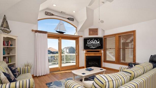 A living room with a large window, a fireplace, and a television.