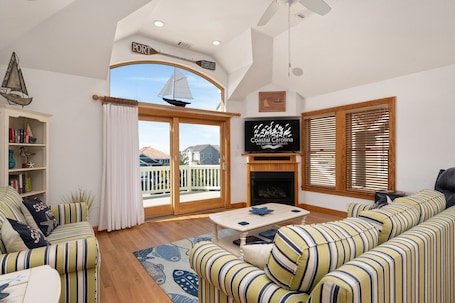 A living room with a large window, a fireplace, and a television.