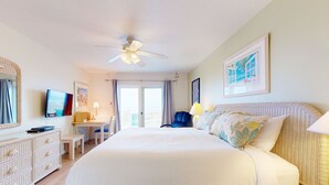 Une chambre spacieuse avec un grand lit, un bureau, une chaise, une télévision et un balcon avec des rideaux.