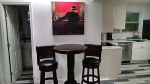 Une petite cuisine avec un coin repas, un tableau accroché au mur et un sol carrelé.