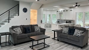A modern living room with grey sofas, a coffee table, and a staircase.