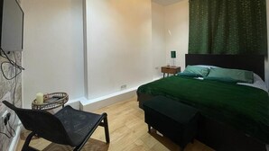 Um quarto com uma cama, mesa de cabeceira, cadeira e abajur.