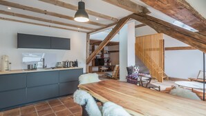 Et moderne køkken med træloft, et spiseområde med et træbord, og en hyggelig siddekrog.