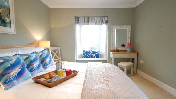 Un dormitorio con cama, mesita de noche, cómoda y ventana con vistas.