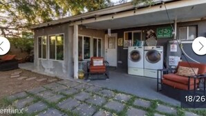 A small, single-story building with a front porch, a washing machine, and a bicycle rack. - Cozy Home in Central Phoenix (Phoenix)