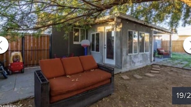 A small house with a patio area, a red couch, and a basketball hoop. - Cozy Home in Central Phoenix (Phoenix)