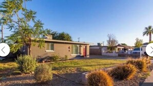 A single-story house with a small front yard, a red door, and a visible garage. - Cozy Home in Central Phoenix (Phoenix)