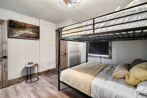 Un lit superposé avec une tête de lit, une table de chevet et un tableau accroché au mur.