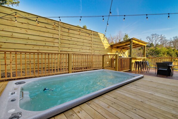 Un bain à remous sur une terrasse en bois, agrémentée d’une pergola et de mobilier d’extérieur.