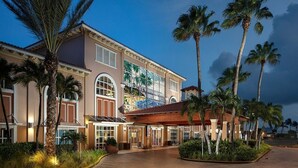 A large, multi-story hotel with a central courtyard, palm trees, and a mosaic mural on the facade.