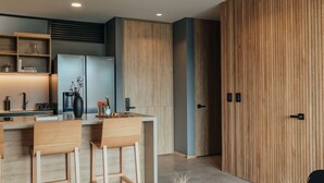 Una cocina moderna con taburetes de madera, una cafetera integrada y un mueble grande de madera.