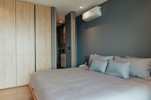 A bedroom with a bed, a wardrobe, and an air conditioning unit.