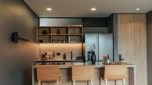 Una cocina moderna con una isla central, sillas de madera y estantes empotrados.