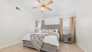 Une chambre à coucher avec un lit, une table de chevet et un ventilateur de plafond.