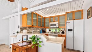 A modern kitchen with wooden cabinets, a white refrigerator, a microwave, and a sink. - Oceanview Townhome, freshly updated in Keauhou, close to Kona. (Keauhou)