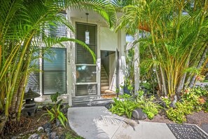 Une maison moderne dotée d’un porche abrité, d’une lanterne en pierre et d’une végétation tropicale luxuriante.