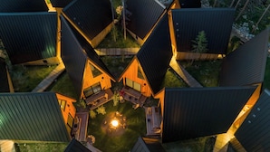 A cluster of modern, angular cabins with a central fire pit surrounded by seating. - A Frame Club  (Winter Park)