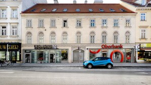 Un immeuble à la façade classique, abritant un salon de coiffure, une banque et où l’on peut apercevoir un vélo sur le trottoir.