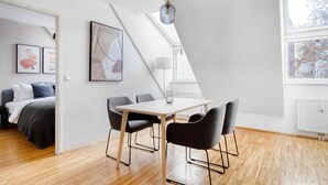 Une chambre moderne comprenant un lit, un bureau et une chaise, ainsi qu’un coin repas avec une table et des chaises.