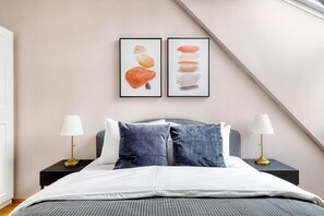 Un dormitorio con una cama, dos mesitas de noche, dos lámparas y dos cuadros en la pared.