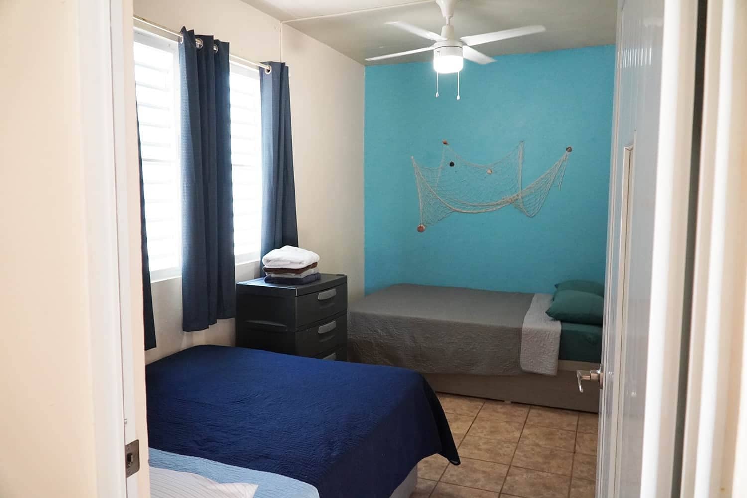 A bedroom with a bed, a nightstand, a ceiling fan, and a hammock.