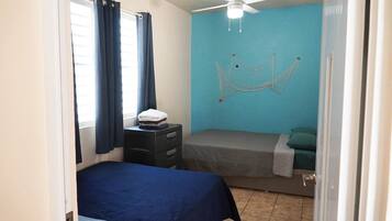 A bedroom with a bed, a nightstand, a ceiling fan, and a hammock.