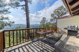 A deck with a table and chairs, overlooking a mountainous landscape.