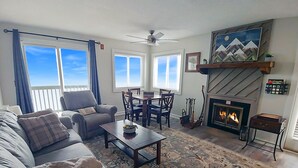 Ein Wohnzimmer mit Sofa, Sessel, Couchtisch, Kamin und Essbereich.