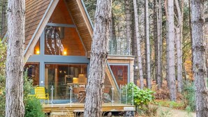 A modern wooden cabin with large windows, a deck, and a forest setting. - Woodpecker, Weybourne, Norfolk (Weybourne)