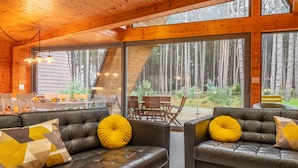 A cozy cabin interior with leather sofas, large windows, and a dining area. - Woodpecker, Weybourne, Norfolk (Weybourne)