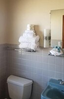 Un baño con inodoro, lavamanos y toallero con toallas dobladas.