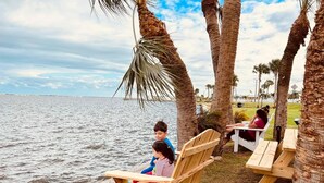 A lakeside park with wooden benches and palm trees. - Treasure Coast Pool Home - Walk to Downtown Jensen Beach. (Jensen Beach)
